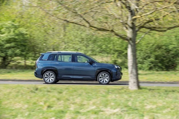 AION V w granatowym lakierze z boku podczas jazdy, widoczna sylwetka SUV-a