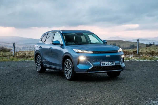 Geely Starray EM-i w kolorze niebieskim, widok od przodu w 3/4, w tle wzgórza i jezioro